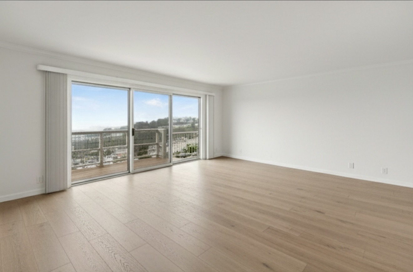 Spacious living room with sliding glass doors to a balcony and distant view.